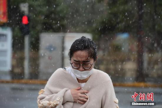 4月3日，民众在雪中裹紧外衣前行。当日，呼和浩特迎来降雪，气温骤然下降，不少民众纷纷加衣保暖。中新社记者 刘文华 摄