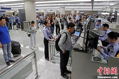 资料图：上海虹桥国际机场T1航站楼内入境大厅，民警为旅客办理通关手续。 中新社记者 殷立勤 摄