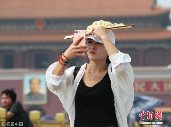 资料图：北京，天安门广场游客遮阳防晒各有各招。图片来源：视觉中国