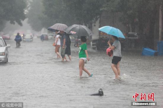 资料图：天津遭遇暴雨天气，街头市民在雨中“湿身”出行。图片来源：视觉中国