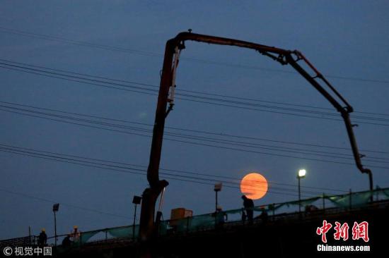 7月27日，江苏省淮安市，建筑工人在月全食前期的红月下施工，构成一幅优美的剪影。周长国 摄 图片来源：视觉中国