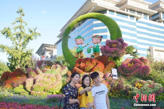 9月23日，游客在北京西单街头“绿色生活”主题花坛前自拍。 中新社记者 张兴龙 摄