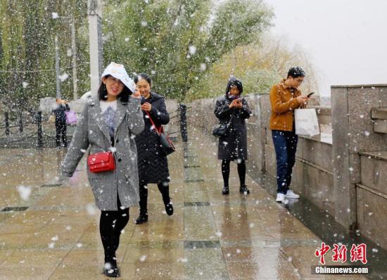 11月14日，甘肃省兰州迎来降雪，顶风冒雪的市民在路边拍照、玩雪。高展 摄