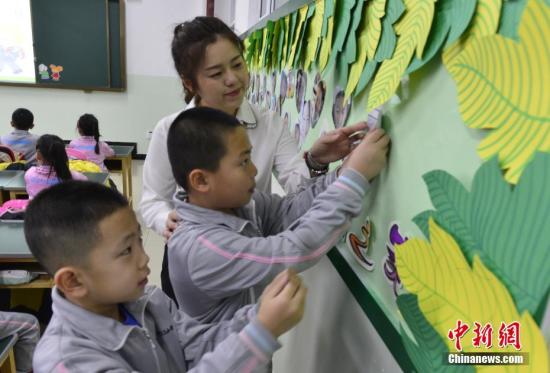 2月27日，新疆乌鲁木齐市第133小学，一年级的学生在老师的指导下将自己的照片贴上笑脸墙。当天，该市52万名中小学生结束假期生活，走进课堂开始新学期第一天的课程。中新社记者 刘新 摄