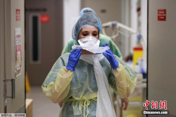 资料图：巴黎附近的巴尼奥莱市一家医院内，医护人员调整自己的防护装备。