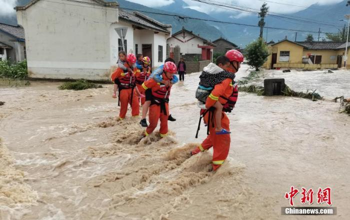 资料图：消防救援人员在洪水中背着孩子们转移。<a target='_blank' href='http://www.chinanews.com/'>中新社</a>发 凉山消防 供图