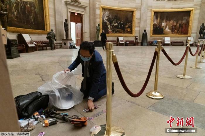 当地时间1月7日，美国华盛顿，特朗普支持者冲入国会大厦引发骚乱后，国会大厦内大量设施被损毁，现场一片狼藉。图为工作人员清理遗留的垃圾。