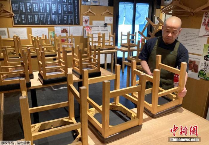 资料图：当地时间2021年1月8日，日本东京，一位餐厅老板正在收拾店内的座椅，准备关店。