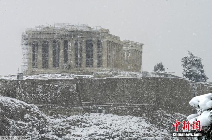 资料图：希腊雅典，古老的卫城被积雪覆盖。图为卫城最高处的帕特农神矗立在纷飞的大雪中。