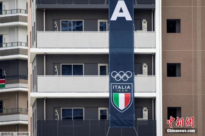 当地时间2021年7月14日，日本东京，距离东京奥运会开幕还有9天时间，运动员陆续搬进奥运村。图为意大利代表队的旗帜悬挂在东京奥运村和残奥会村的一栋建筑上。