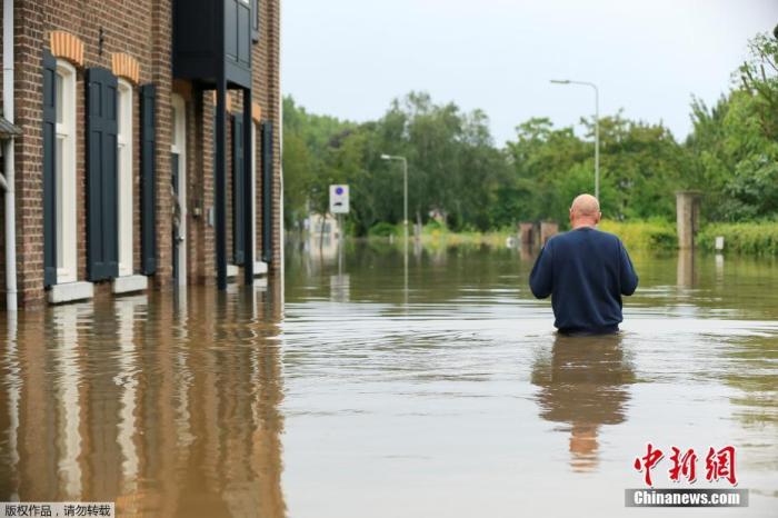 当地时间7月16日，荷兰Guelle，居民在洪水中涉水前进。