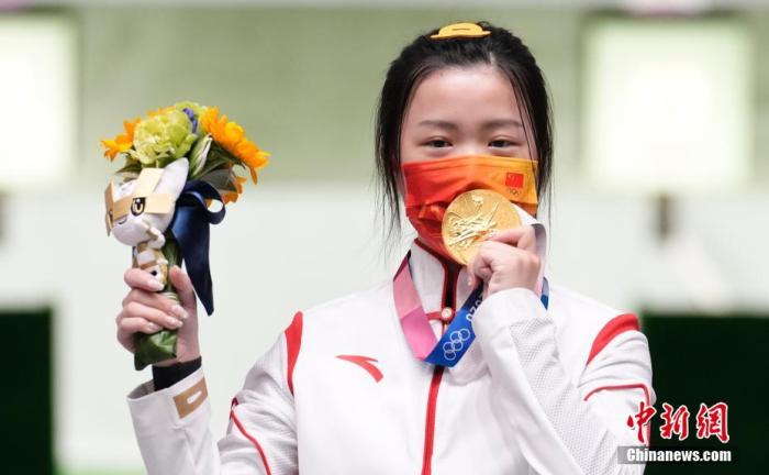 7月24日举行的东京奥运会女子10米气步枪决赛中，中国选手杨倩夺得冠军，为中国代表团揽入本届奥运会第一枚金牌。这也是本届东京奥运会诞生的首枚金牌。图为杨倩隔着口罩亲吻金牌。<a target='_blank' href='/'>中新社</a>记者 杜洋 摄