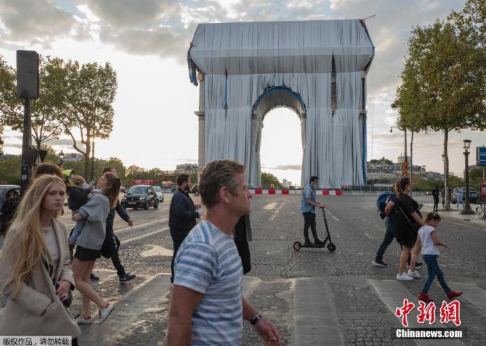 当地时间9月12日，法国巴黎，人们走过被银蓝色织物包裹的凯旋门。据报道，这个项目是由已故著名大地艺术家克里斯托设计。为尊重克里斯托的遗愿，《包裹着的凯旋门》项目将按原计划，将于9月18日至10月3日在巴黎展出。出生于保加利亚的克里斯托长期居住在巴黎，他被人们称为世界上最重要的大地艺术家之一。