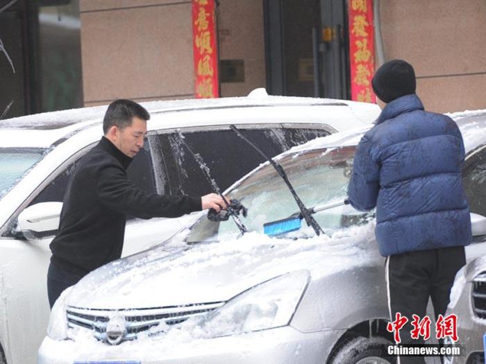 市民在清理车上的积雪。张瑶 摄