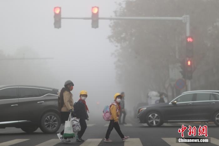 11月18日，民众在浓雾中出行。当日早上，北京通州、大兴等多区升级发布大雾橙色预警信号，局地能见度小于200米。 中新社记者 杨可佳 摄