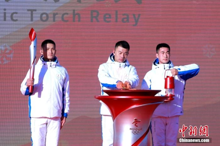 2月2日上午，北京2022年冬奥会火炬接力启动仪式在北京奥林匹克森林公园举行。图为火种护卫从火种灯中引出火种，点燃火种台。 中新社记者 李纯 摄    