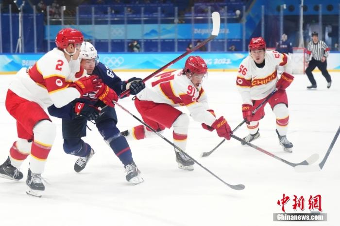2月10日，在国家体育馆举行的北京2022年冬奥会男子冰球小组赛中，中国队对阵美国队。图为中国队球员和美国队球员在比赛中拼抢。 中新社记者 毛建军 摄  