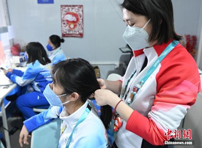3月8日，“国际劳动妇女节”当天，北京2022年冬残奥会赛场上下的女性们各展风采。图为张家口国家冬季两项中心场馆媒体中心的一名工作人员(右)在工作间隙为志愿者编发辫。 中新社记者 侯宇 摄