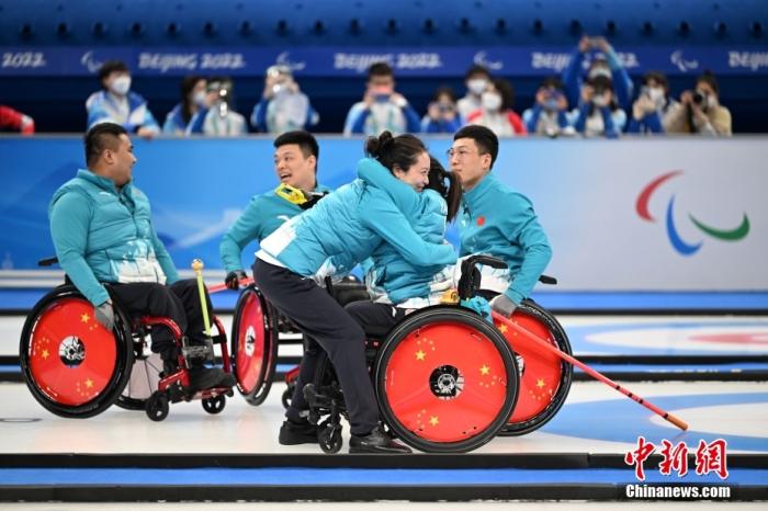 3月12日，中国轮椅冰壶队教练岳清爽（右三）在比赛后拥抱队员庆祝。 中新社记者 刘冉阳 摄