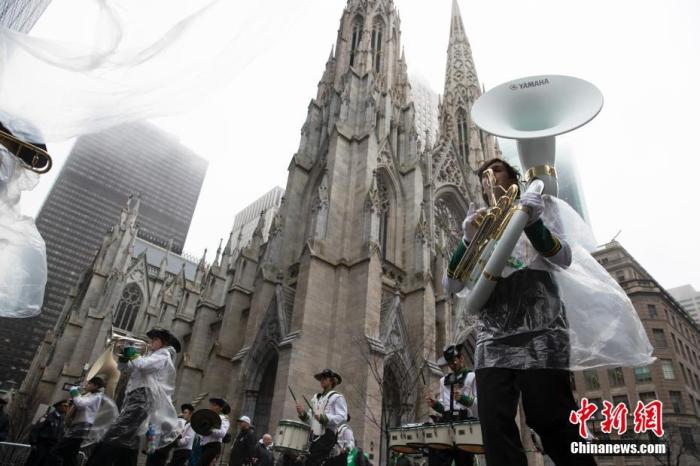 当地时间3月17日，纽约圣帕特里克节游行在降雨天气中举行，游行人员穿着雨披经过圣帕特里克教堂。