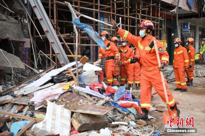 资料图：救援人员清理外围倒塌物。 杨华峰 摄
