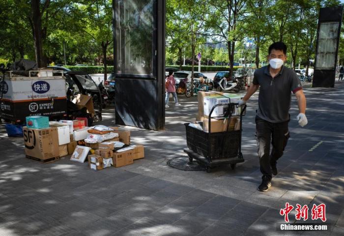 资料图：5月13日上午，一名快递员准备将一批快件送往北京市朝阳区望京街道的一个居民小区的收件客户。中新社记者 侯宇 摄