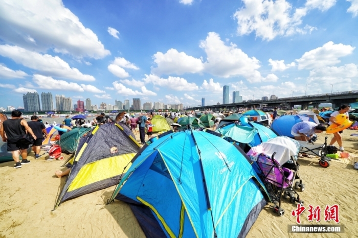 资料图：哈尔滨市民们在松花江畔的沙滩浴场里扎起帐篷。 中新社记者 孙汉仑 摄
