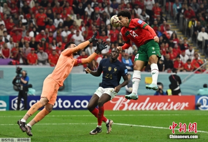 摩洛哥队球员(红)头球攻门。