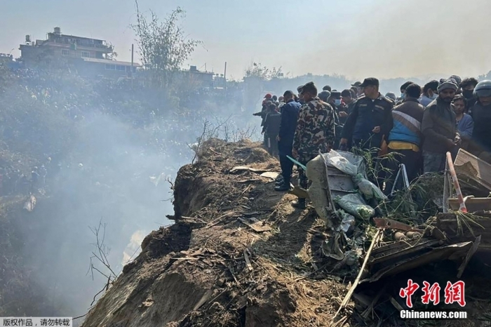 当地时间1月15日上午，尼泊尔雪人航空公司一架从加德满都飞往博克拉的客机在博克拉旧机场和新机场之间的位置坠毁，机上载有68名乘客和4名机组人员。图为救援人员和人群聚集在飞机残骸周围。