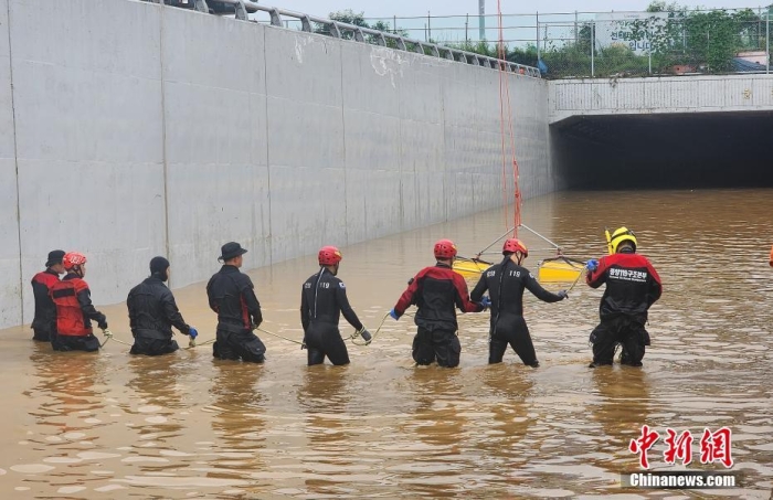 韩国救援人员沿着一条被洪水淹没的道路搜寻失踪人员，这条道路通往被洪水淹没的地下隧道。视觉中国