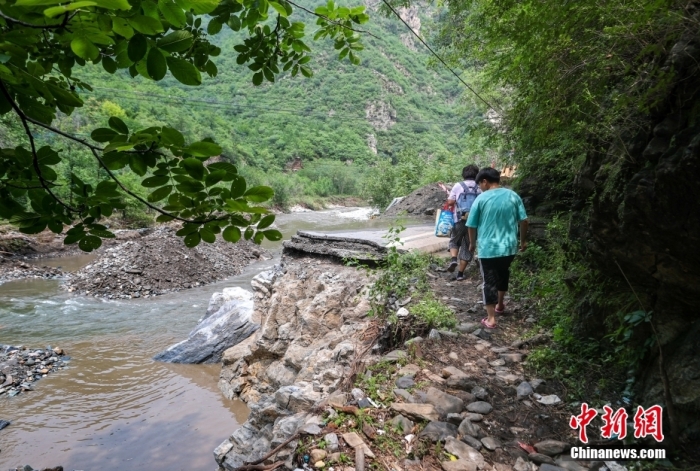 8月4日，北京市房山区，村民走过一处路基坍塌的路段。<a target='_blank' href='/'>中新社</a>记者 贾天勇 摄