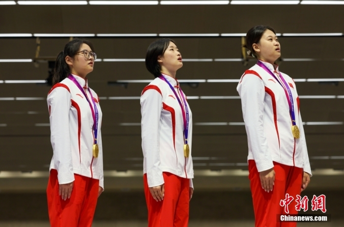 9月27日，杭州第19届亚运会射击女子50米步枪3种姿势团体赛举行，中国队以1773的总分取得金牌。图为中国选手韩佳予、夏思钰、张琼月(从左至右)在颁奖仪式上唱国歌。
中新社
记者 贾天勇 摄