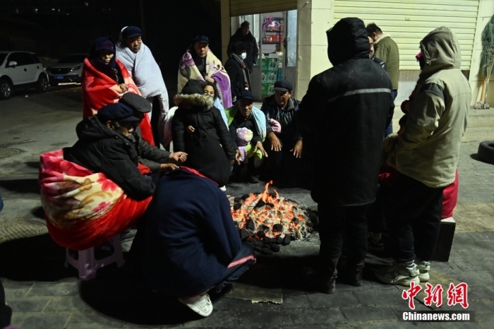 12月19日凌晨，甘肃省临夏州积石山县，居民在街边生火过夜。
中新社
记者 李亚龙 摄