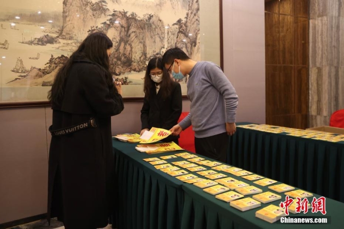 2月27日，在2024年全国两会即将召开之际，位于北京梅地亚中心的全国两会新闻中心正式启用。图为媒体记者在新闻中心领取证件。
中新社
记者 蒋启明 摄